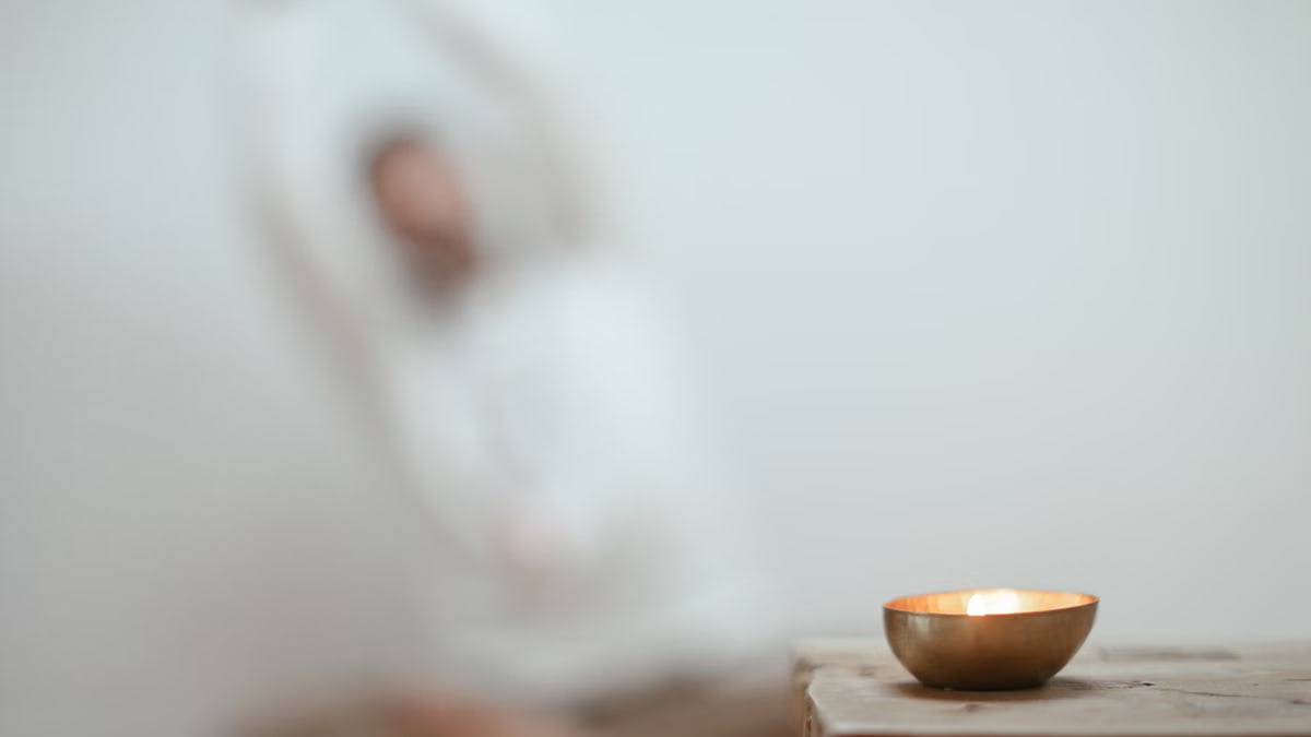 Calm scene with a singing bowl and blurred yoga pose, promoting tranquility.